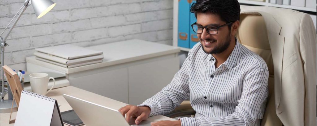 Indian American Small Business Man working on laptop at desk