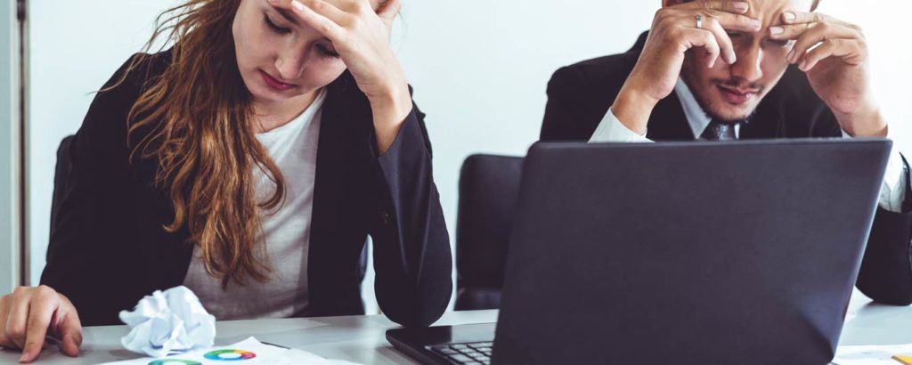 Stressed out man and women business workers at table in front of laptop