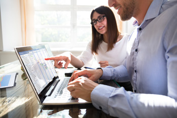 Two Accountants Analyzing Time Sheet Chart On Laptop