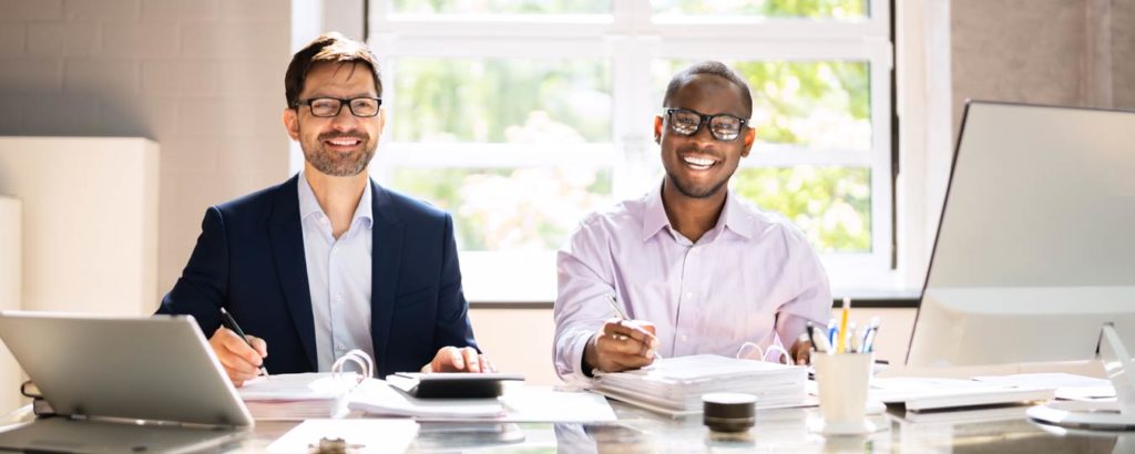 Two happy male accountants sitting at a desk
